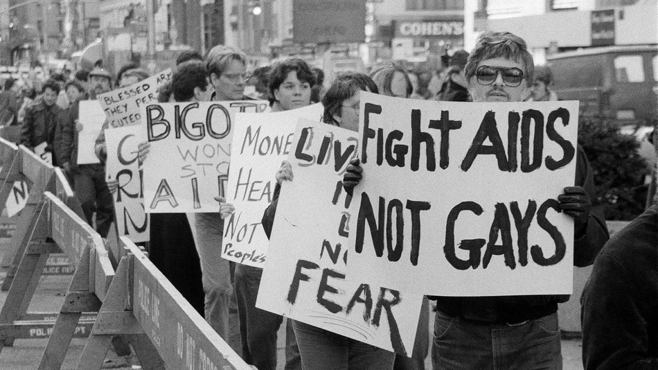 Protesters with signs saying things such as "Fight AIDS, not Gays"